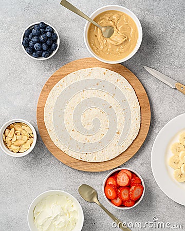 Tortilla cooking process with different fillings of peanut butter, banana, strawberry, blueberry, almond. Food trend Stock Photo