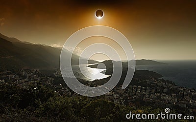 Total solar eclipse in dark red glowing sky above seaside city Stock Photo