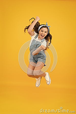 Totally happy. Energy inside. Feeling free. Summer holidays. Jump of happiness. Small girl jump yellow background. Enjoy Stock Photo