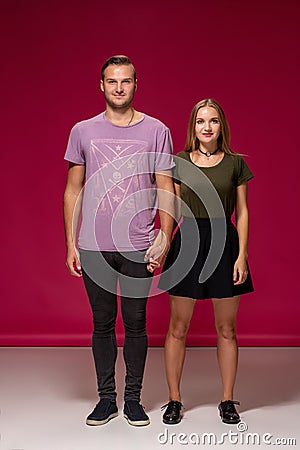 Totally in love. Full length of beautiful young couple embracing and smiling while standing against burgundy background Stock Photo