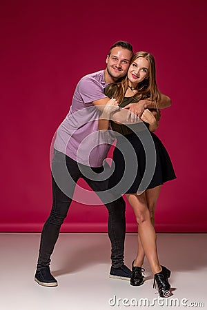 Totally in love. Full length of beautiful young couple embracing and smiling while standing against burgundy background Stock Photo