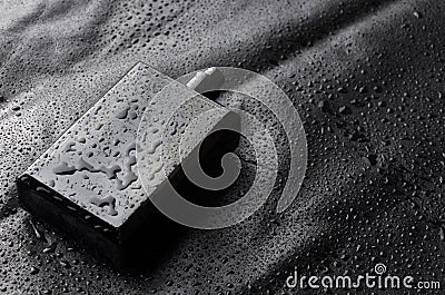 Black bottle of parfume with open cap on black water drops background.Closeu shot Stock Photo