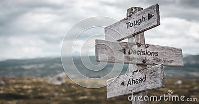 Tough decisions ahead text engraved on wooden signpost outdoors in nature. Stock Photo