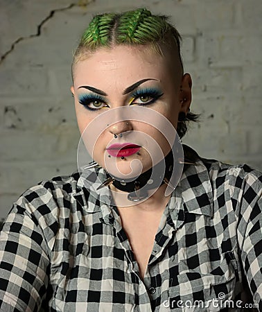 Tough looking punk girl. Facial piercings & green hair, spiked collar. Stock Photo