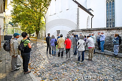 A tour group pauses to listen to a tour guide on a cobblestone street in medieval old town of Tallinn Estonia Editorial Stock Photo