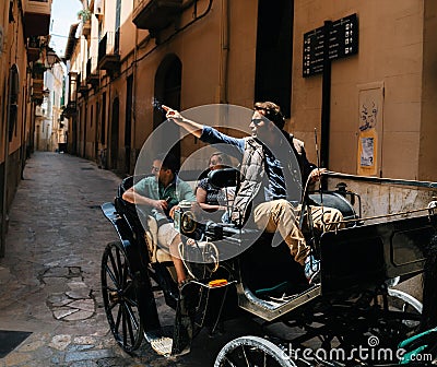 Tour guide in horse carriage points a hand at a landmark, Mallorca, Spain Editorial Stock Photo