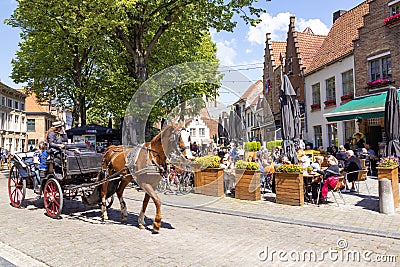 Tourism in Belgium. Medieval houses, cafes with tourists, a horse and cart Editorial Stock Photo