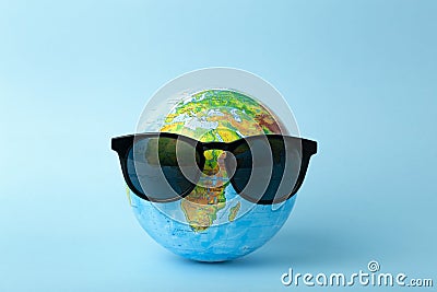 Tourism, ecology, vacation and globalism concept. Globe in sunglasses on a blue background banner. Minimal creative Stock Photo