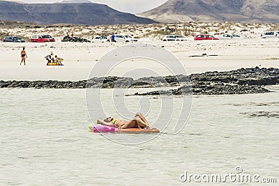 Tourism and tourists concept in summer holiday vacation - nice woman enjoying sunbath on a coloured lilo in the sea water at the Stock Photo