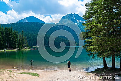 Tourist attraction of Durmitor National Park. Man tourist near glacial Black Lake with Meded Peak Editorial Stock Photo