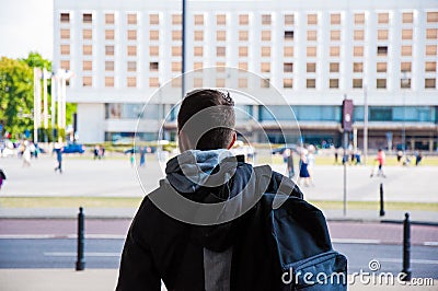 Tourist with backpack from the back, rear. Traveller among the city, with walking blurred people in the background Stock Photo