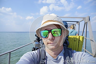 Tourist with a backpack takes a selfie on the camera at the sea pier Stock Photo