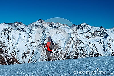 Tourist with backpack and trekking poles walking walking in the snowy mountains at sunny day Editorial Stock Photo