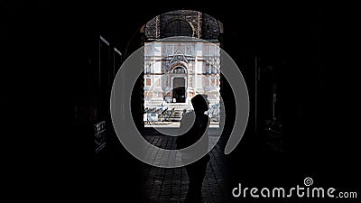 tourist from behind in the arcades in Piazza Maggiore in Bologna with the Unfinished Church in the background. Italy Editorial Stock Photo