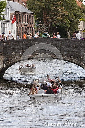 Tourist boat in bruges canal under old bridge on sunny summer da Editorial Stock Photo