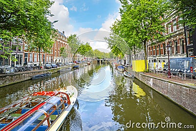 A tourist boat travels a picturesque canal in Amsterdam Editorial Stock Photo