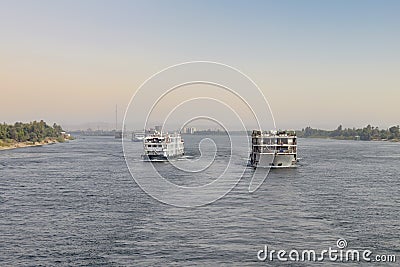 Tourist boats on the Nile river near Aswan. A fleet of floating hotels tourist boats motor down the River Nile towards Aswan in Stock Photo