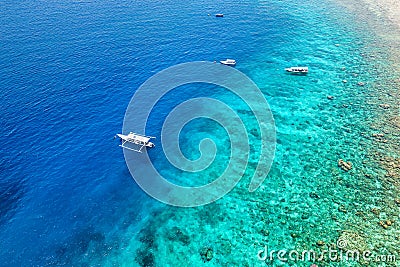 Tourist boats over the wall of a fringing coral reef in Indonesia Stock Photo