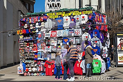 Tourist buying a souvenir gift at a street market stall selling clothing and footballs Editorial Stock Photo
