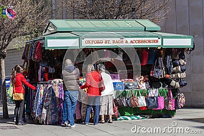 Tourist buying a souvenir gift at a street market stall selling leather handbags and accessories Editorial Stock Photo