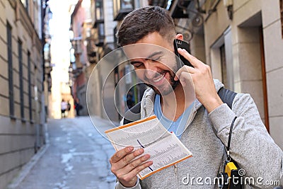 Tourist calling by phone while looking at tourism guide or dictionary Stock Photo