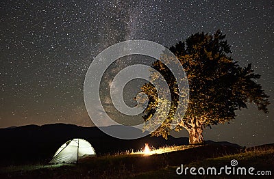 Tourist camping at night in the mountains under starry sky Stock Photo