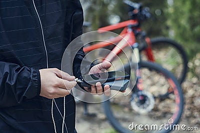 A tourist charges a smartphone with a power bank on the background of a bicycle in nature Stock Photo