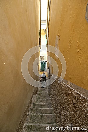 Tourist climbs a steep staircase in a narrow alley in the center of the village Editorial Stock Photo