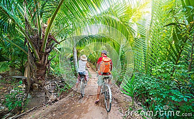 Tourist couple riding bicycle in the Mekong Delta region, Ben Tre, South Vietnam. Woman and man having fun cycling on trail among Stock Photo