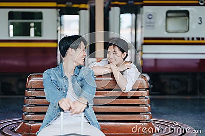 Tourist couples showing their love and happiness in a sweet way while waiting for their journey at the train station. Stock Photo