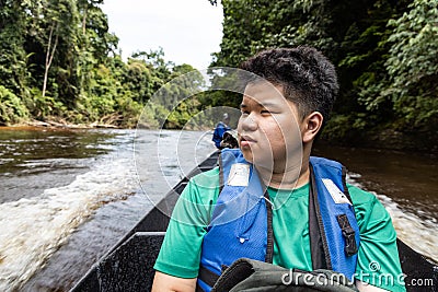 Tourist enjoying scenic nature view of Tembeling river cruise with lush rainforest foliage at Taman Negara National Park Stock Photo
