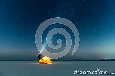 Tourist with flashlight near yellow tent lighted from the inside Stock Photo