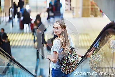 Tourist girl with backpack and carry on luggage in international airport, on escalator Stock Photo