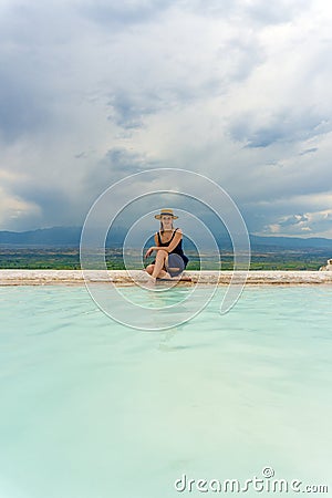 Tourist girl in dress with hat in Natural travertine pools and terraces in Pamukkale. Cotton castle in Turkey. Woman in pamukkale. Stock Photo