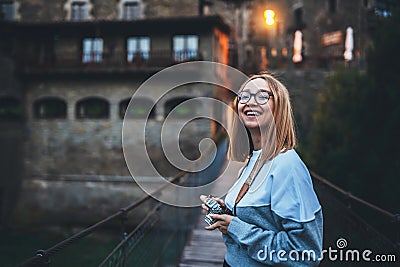 Tourist girl look at the camera and laugh walking old historical city and hold in hands retro camera Stock Photo