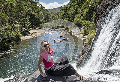 Tourist girl sitting on the rock at the edge of waterfall at the national park Stock Photo