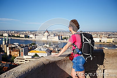 A tourist girl is standing with her back in the observation deck at the altitude overlooking the parliament in Hungary, Budapest c Stock Photo