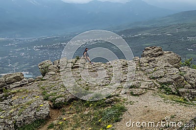 A tourist girl standing on a rock and admires the Demerdzhi mountain range on the Crimean peninsula Stock Photo