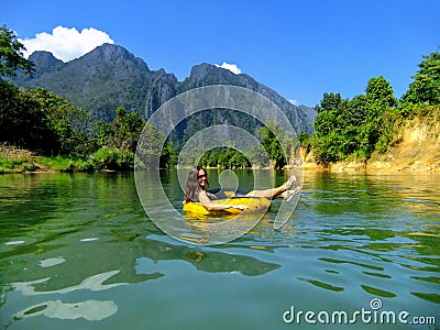 Tourist going down Nam Song River in a tube surrounded by karst Stock Photo