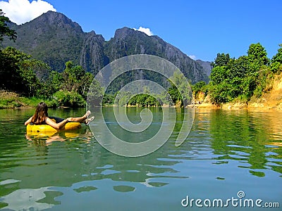 Tourist going down Nam Song River in a tube surrounded by karst Stock Photo