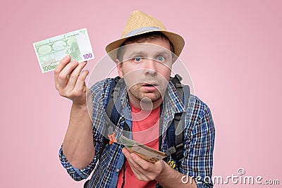 Tourist in hat holds euro bank note checking it Stock Photo