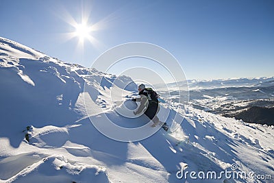 Tourist hiker climber in winter clothing with backpack climbing dangerous rocky steep mountain slope covered with deep snow, white Stock Photo