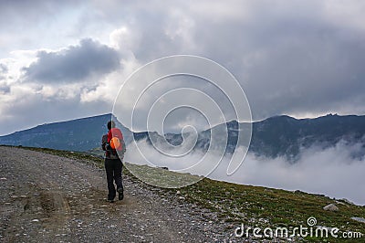 Tourist hiking on a high path in the mountains. Stock Photo