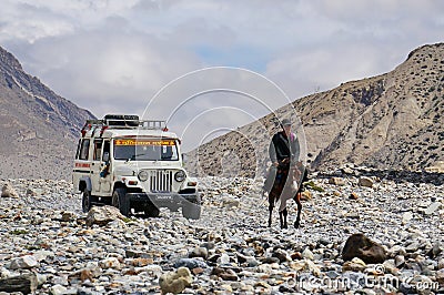 A tourist jeep and a local resident riding a horse among the Himalayan mountains on the way to Upper Mustang Editorial Stock Photo