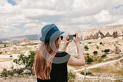 A tourist makes a photo on the phone in memory of a beautiful view of the hills in Cappadocia in Turkey. Travel, tourism Stock Photo