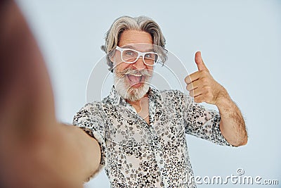 Tourist makes selfie. Senior stylish modern man with grey hair and beard indoors Stock Photo