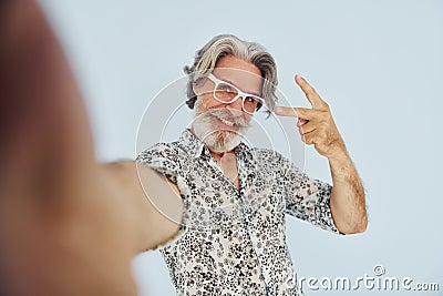 Tourist makes selfie. Senior stylish modern man with grey hair and beard indoors Stock Photo