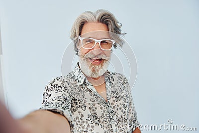 Tourist makes selfie. Senior stylish modern man with grey hair and beard indoors Stock Photo