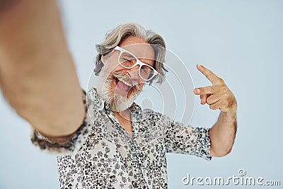 Tourist makes selfie. Senior stylish modern man with grey hair and beard indoors Stock Photo