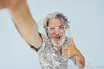 Tourist makes selfie. Senior stylish modern man with grey hair and beard indoors Stock Photo